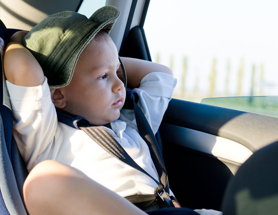 Niño pequeño viajando en la parte de atrás de un coche con su silla