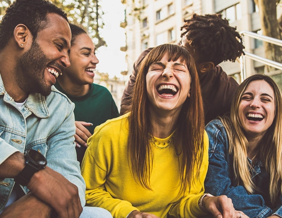 Grupo de gente sentada en una escaleras riéndose